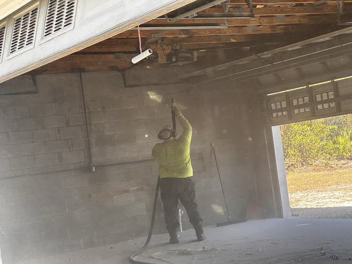 Operator media-blasting a concrete block wall