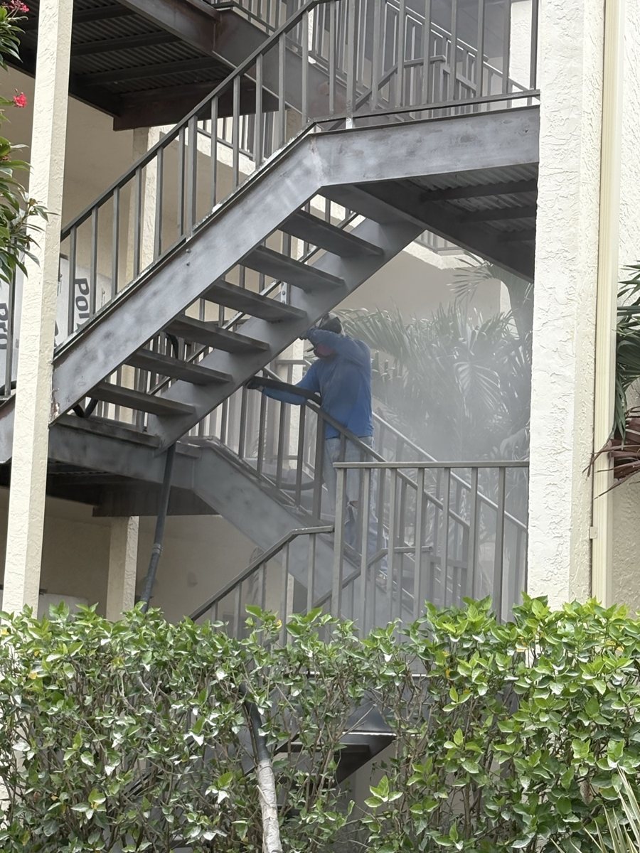 Worker blasting a steel stairwell at a condo building